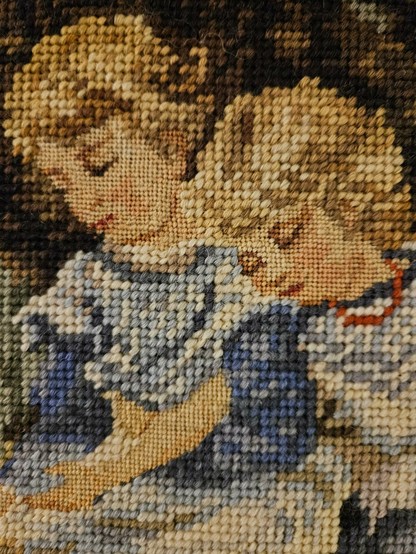 A detail of the crossstitch picture, showing that the faces and hands are stitched in smaller stitches, allowing for more details.